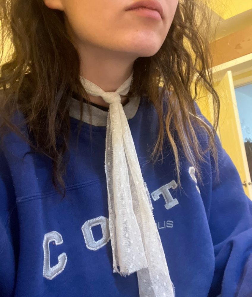 girl wears a piece of lace as a tie and a bright blue sweatshirt